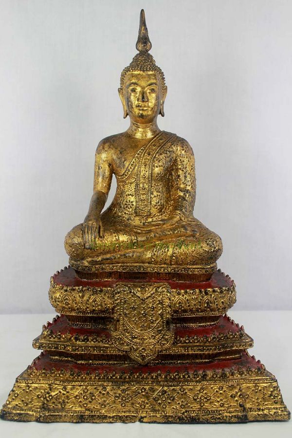 a golden buddha statue sitting on top of a red and gold base with a white background