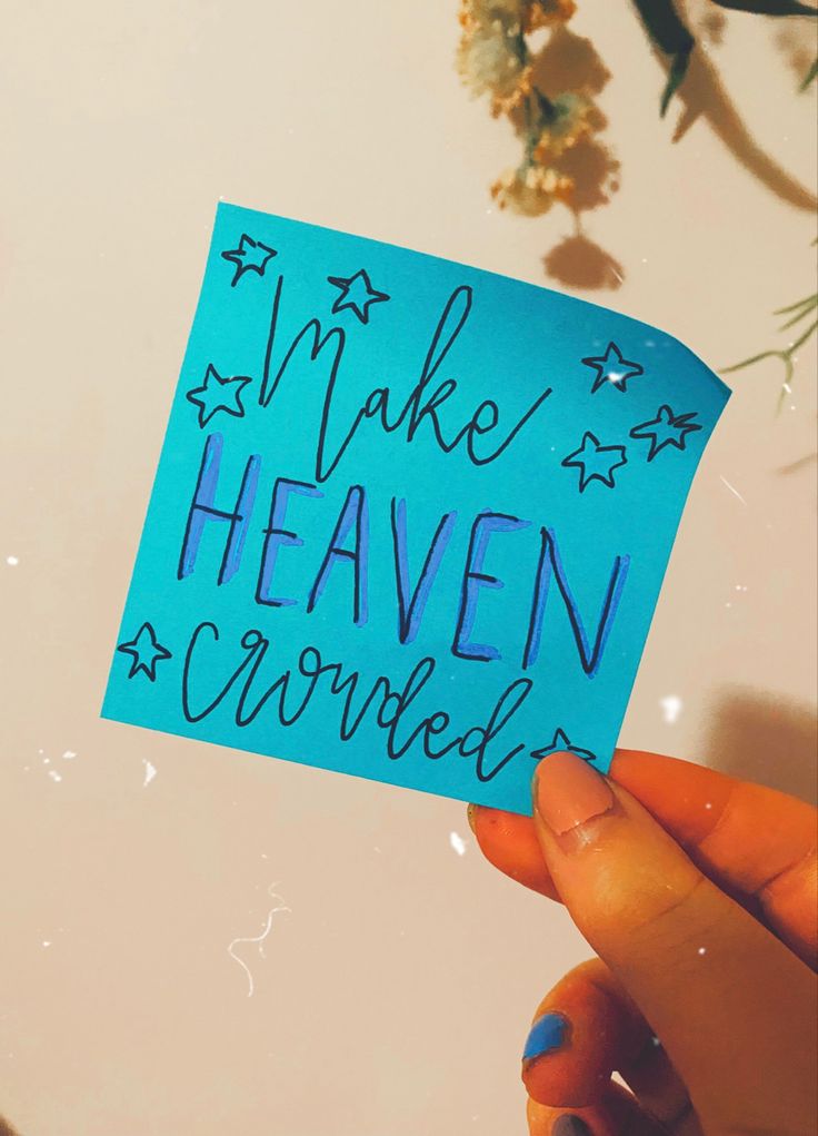 someone holding up a piece of blue paper with writing on it that says make heaven covered