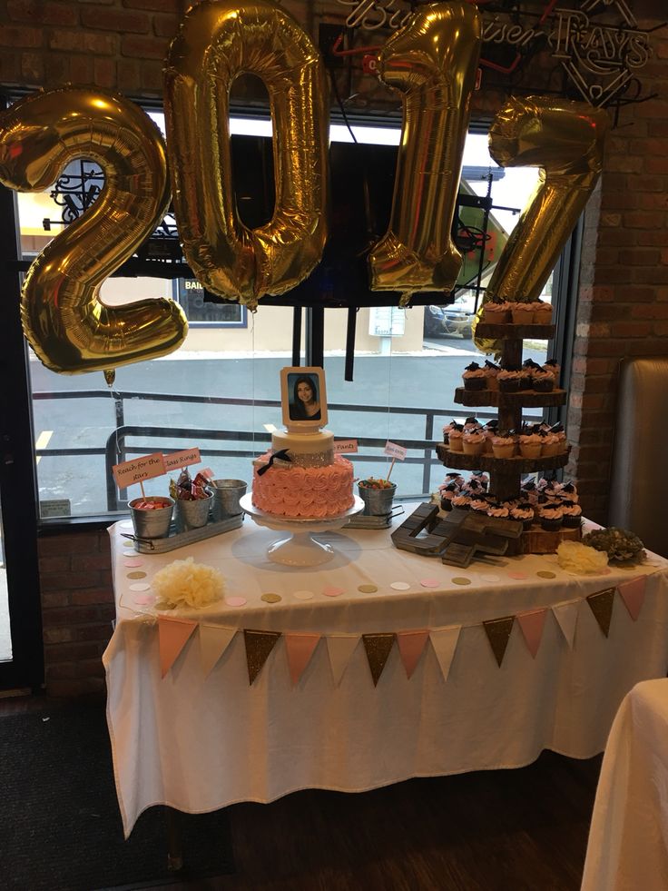 a table topped with lots of cake and balloons next to a sign that says 2013