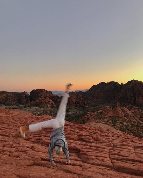 a man doing a handstand on top of a rock formation in the desert