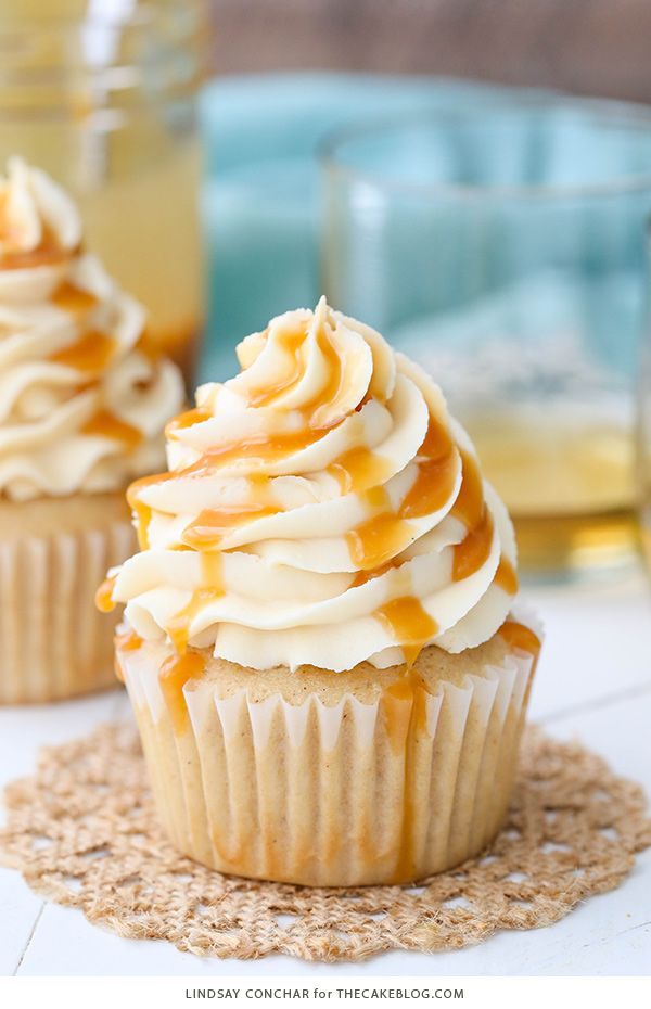 cupcakes with caramel and white frosting on a cork board tablecloth