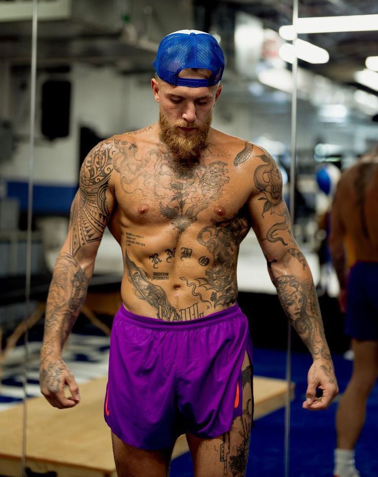 a man with tattoos on his chest and purple shorts