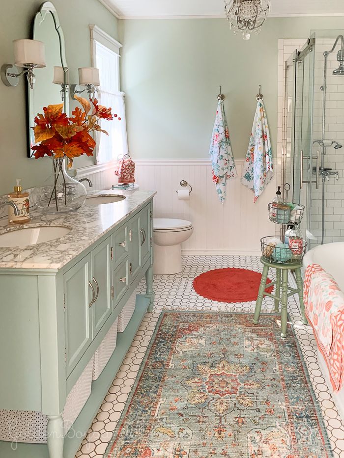 a bathroom with blue cabinets and rugs on the floor