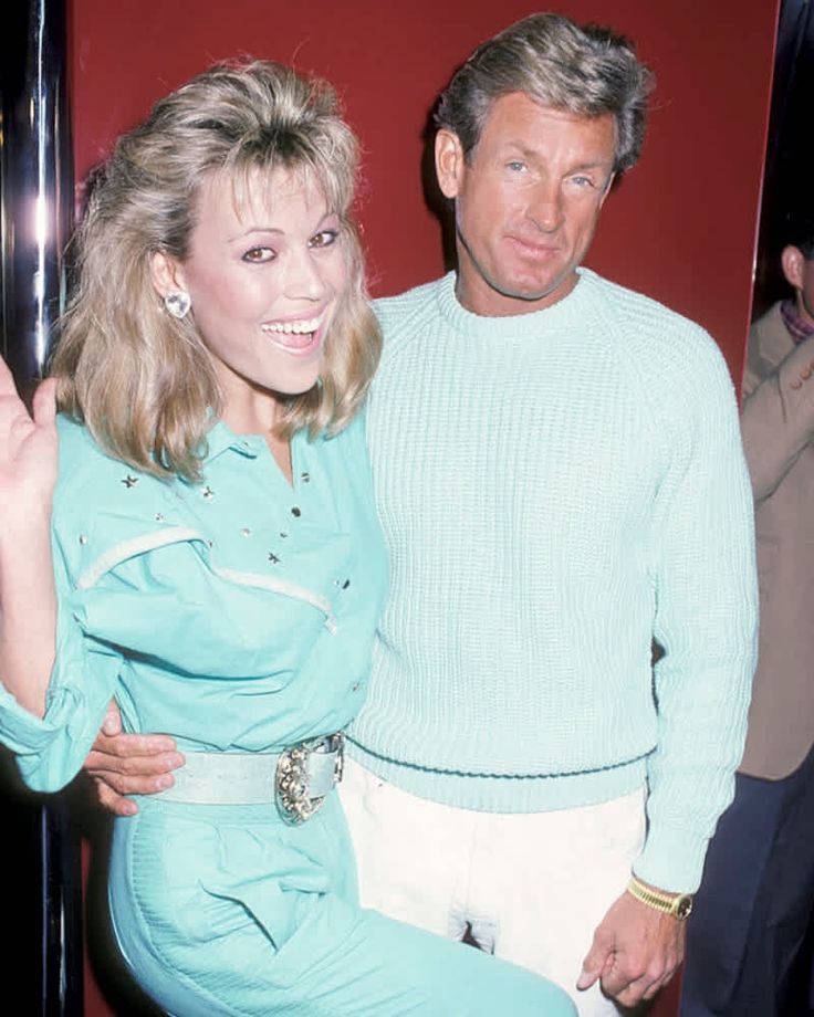 the man and woman are posing together in front of a red wall wearing matching outfits