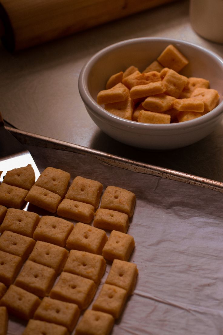 there are many pieces of food on the counter next to a bowl and spoons