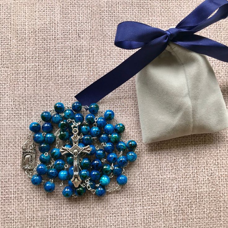 "Catholic Rosary Beads Necklace. Made and blessed in Jerusalem Holy Land Bead color: navy / multicolor Cross color - silver tone Drop length - Approximately 22\"-22.4\" ( 56-57 cm ). Approximate crucifix size -1.75\"x1\" Comes in a pouch as pictured. Silver tone metal Catholic Crucifix Cross with beautiful double sided center piece. If you have any questions, feel free to ask us. We are based in Florida and ship packages every business day very Fast and absolutely FREE! God Bless You and Your Fa Colorful Beads Rosary As Gift, Blue Spiritual Beads With Colorful Details, Blue Beaded Rosary As A Gift, Adjustable Blue Beaded Rosary, Gift Of Blue Polished Beads, Adjustable Rosary With Large Beads As Gift, Beaded Rosary With Oval Beads As Gift, Spiritual Blue Rosary With Round Beads, Adjustable Large Beads Rosary As Gift