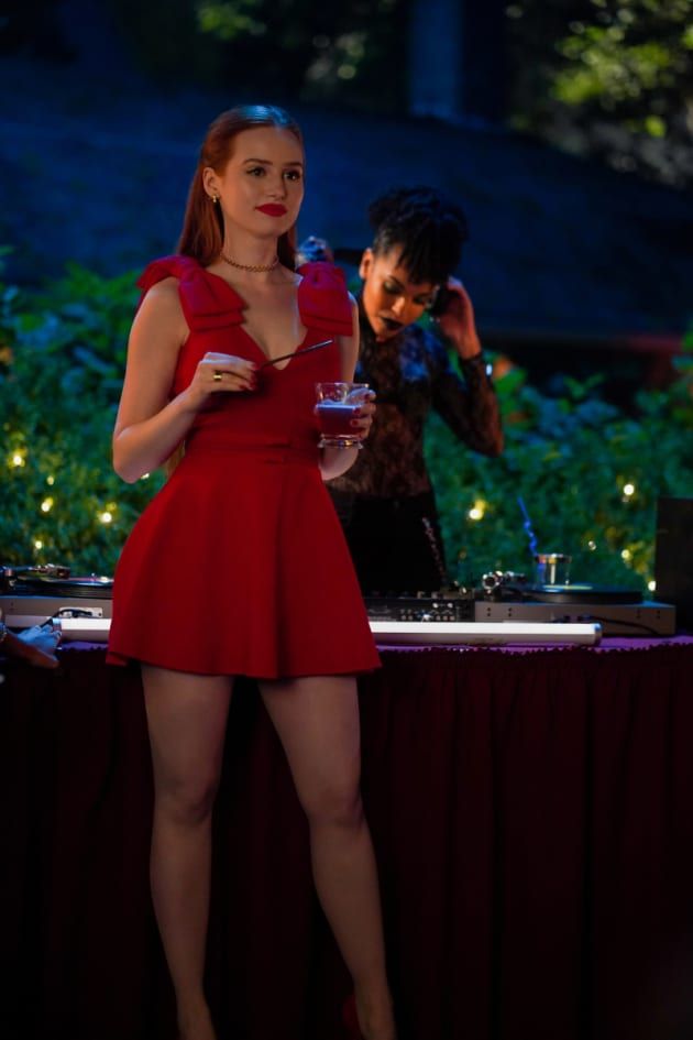 a woman in a short red dress standing next to a dj