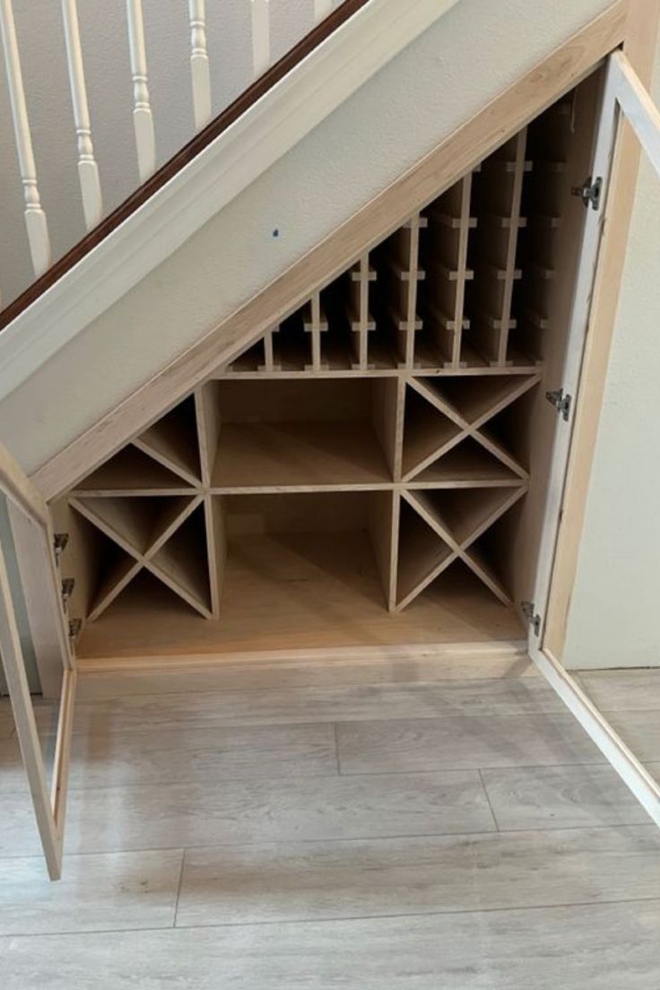 a wine rack under the stairs in a house