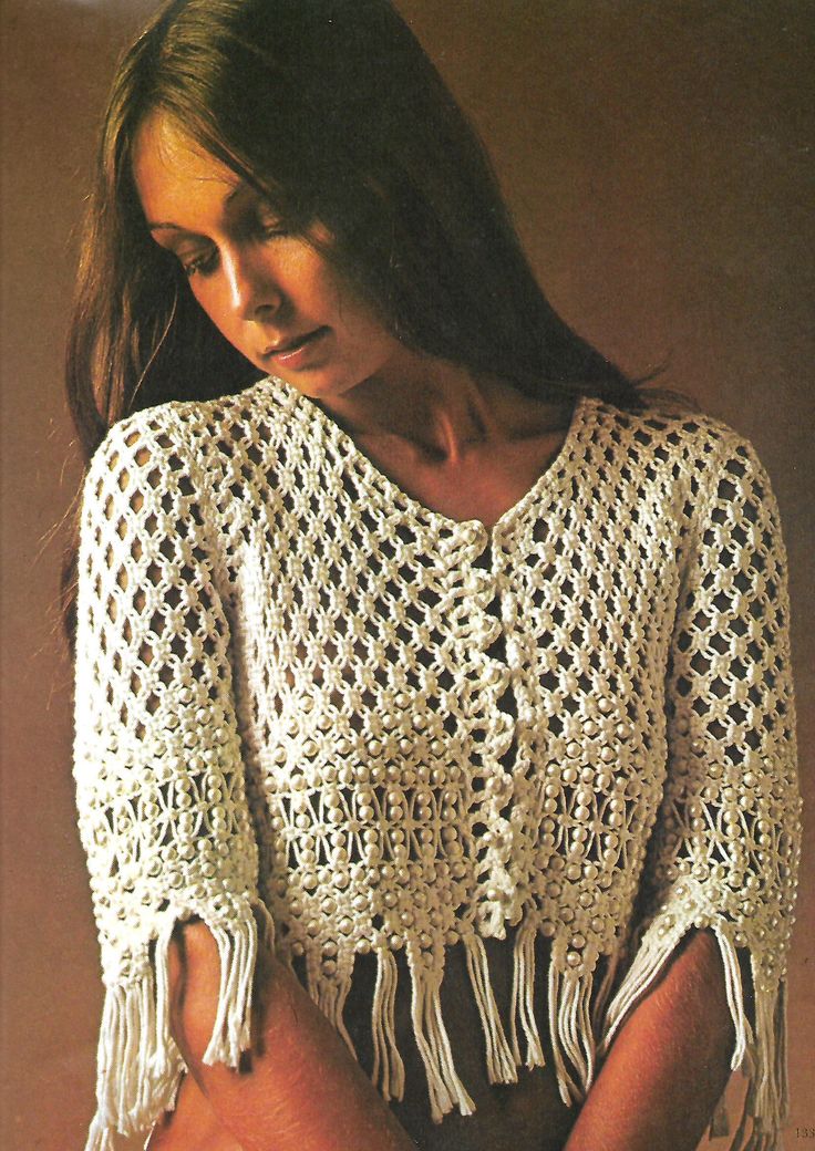 a woman wearing a crocheted sweater with fringes