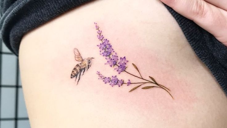 a woman with a tattoo on her stomach has a flower and a bee in it