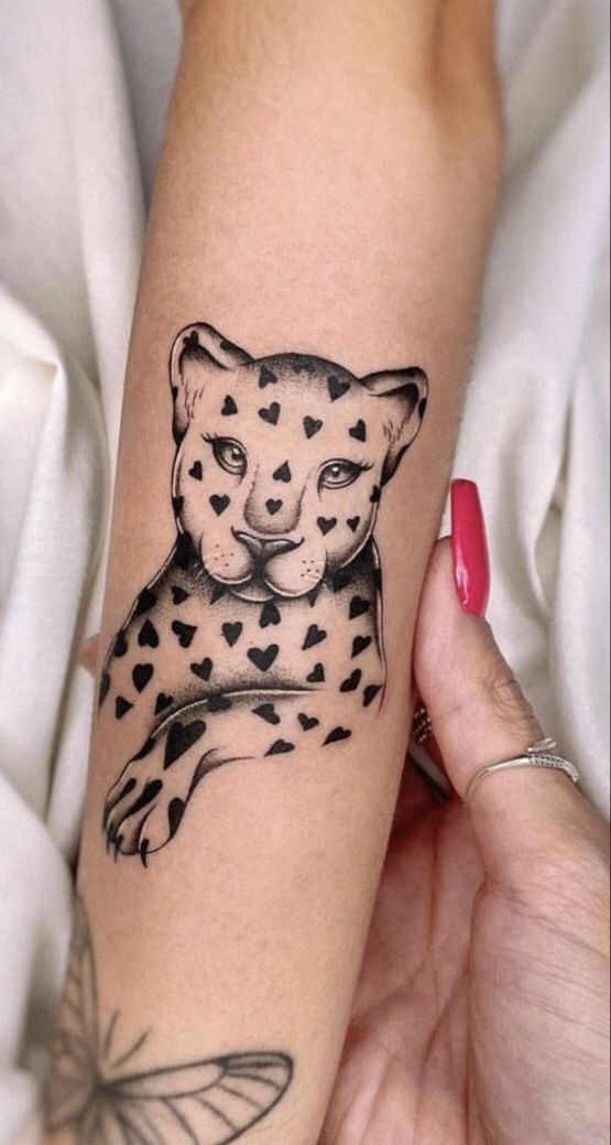 a woman's arm with a tattoo of a cheetah and butterflies on it