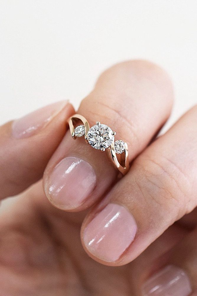 a woman's hand holding an engagement ring with two diamonds on it and the middle finger