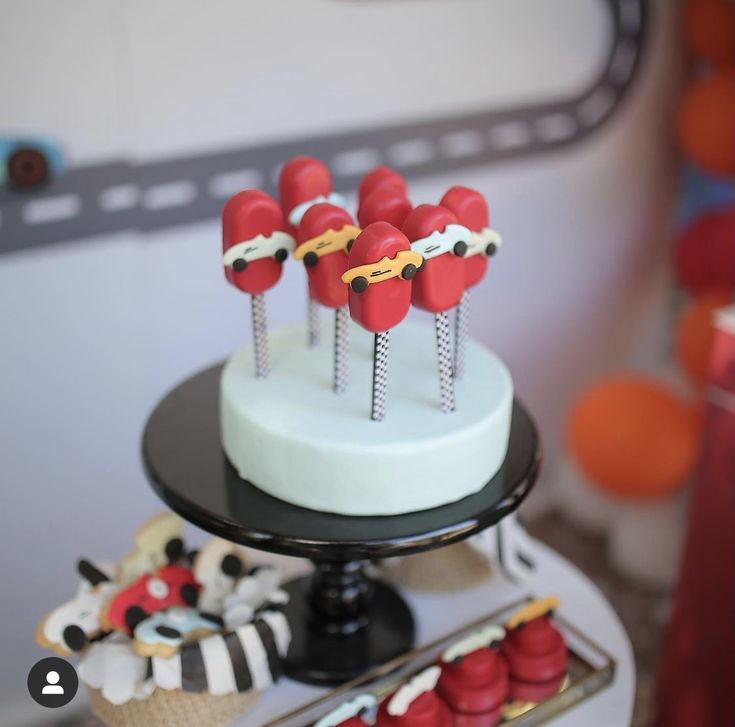 a cake with red and white frosting on it sitting next to other desserts