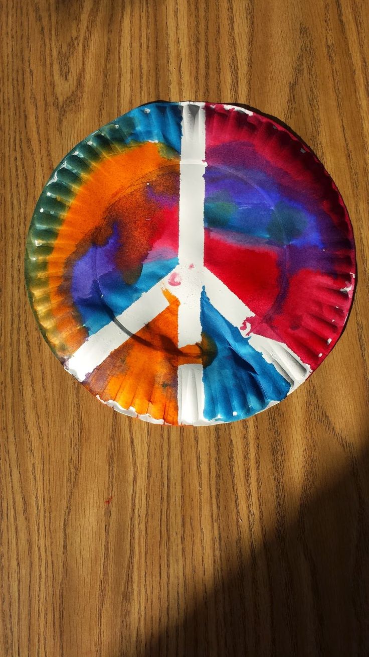 a paper plate with a peace sign painted on it sitting on top of a wooden table