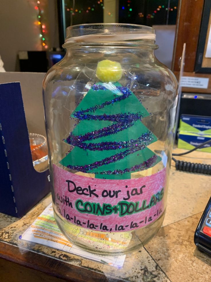 a glass jar with some writing on it and a christmas tree in the bottom half