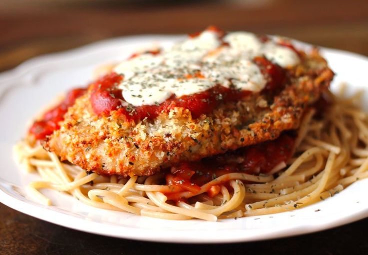 two pieces of chicken parmesan on top of spaghetti