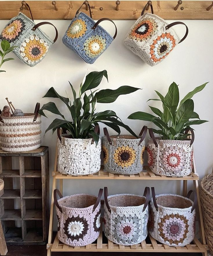 several crocheted baskets are hanging on the wall next to two planters and one is holding potted plants