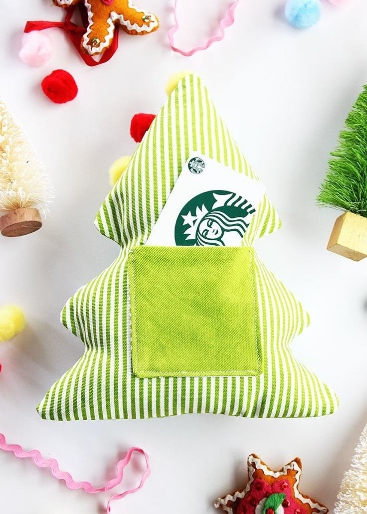 a starbucks christmas tree ornament on a white surface surrounded by other holiday decorations