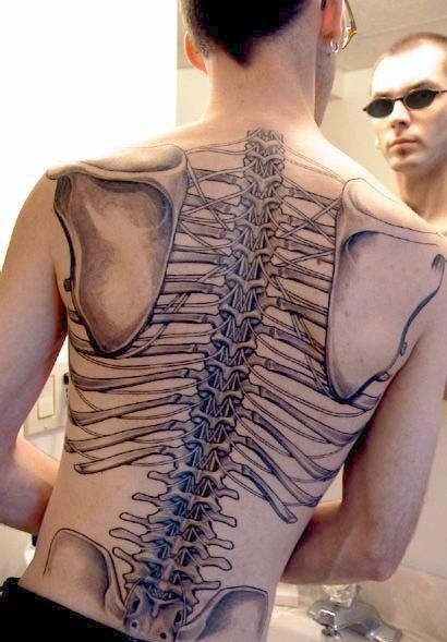 a man with a skeleton back tattoo on his upper half is looking at himself in the mirror