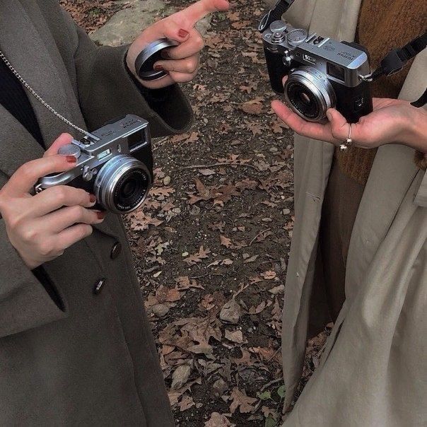 two people holding up cameras in their hands