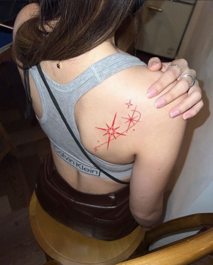 the back of a woman's shoulder with a red tattoo on her left arm