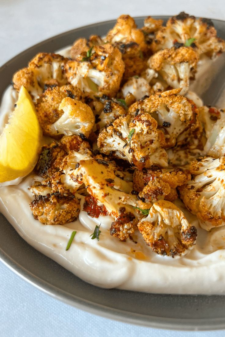 a plate topped with cauliflower and lemon wedges