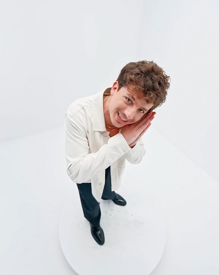 a young man in a white shirt and black tie posing for a photo with his hands on his face