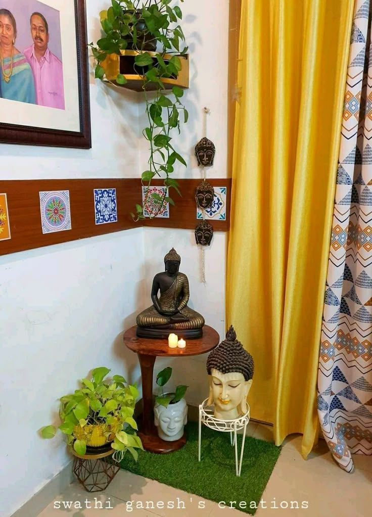 there is a small table with two buddha statues on it in front of a yellow curtain