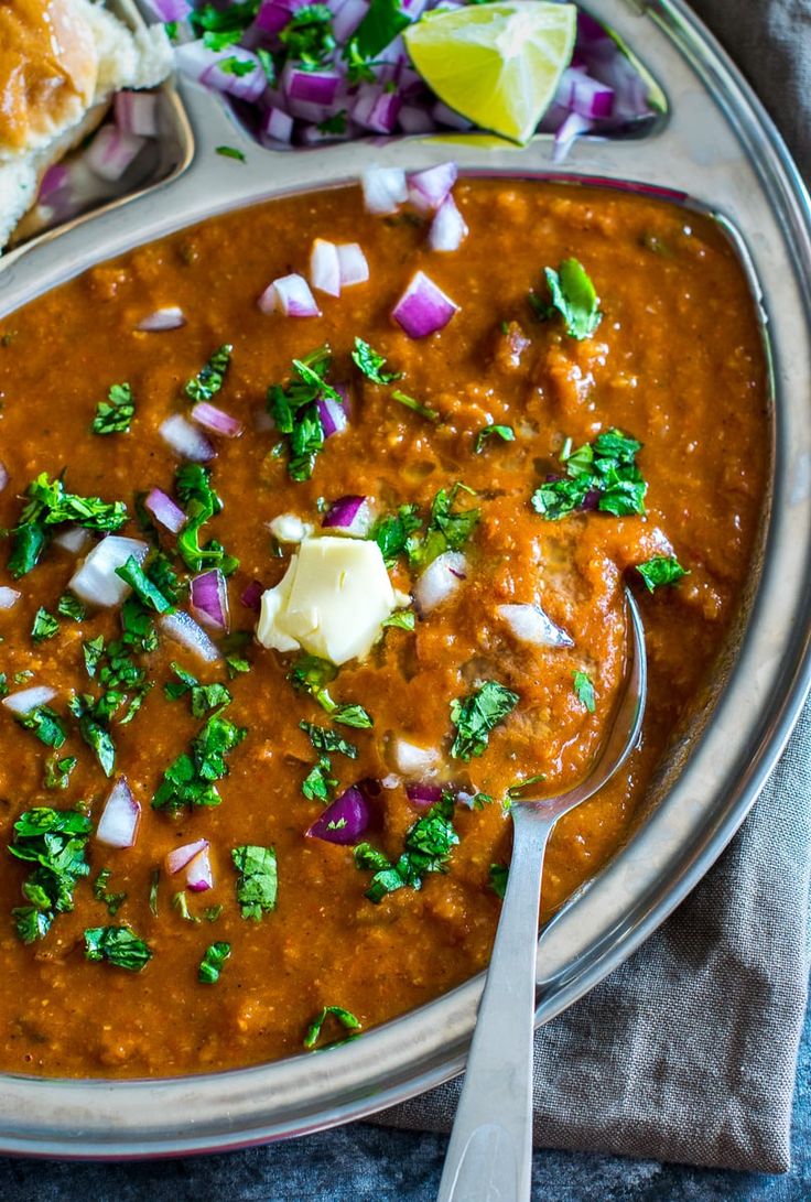 a bowl filled with red beans and onions next to a sandwich on a tablecloth