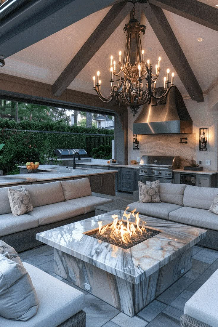 a living room with couches and a fire pit in the center, surrounded by an outdoor kitchen