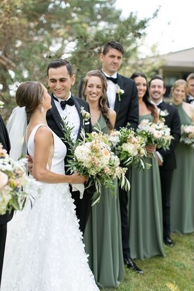 a bride and groom kissing in front of their wedding party