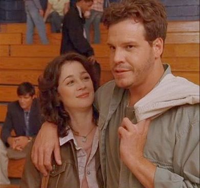 a man and woman standing next to each other in front of a bleachers