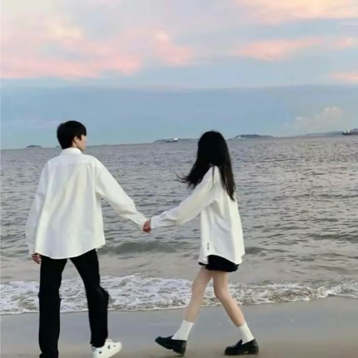 two people holding hands while walking on the beach