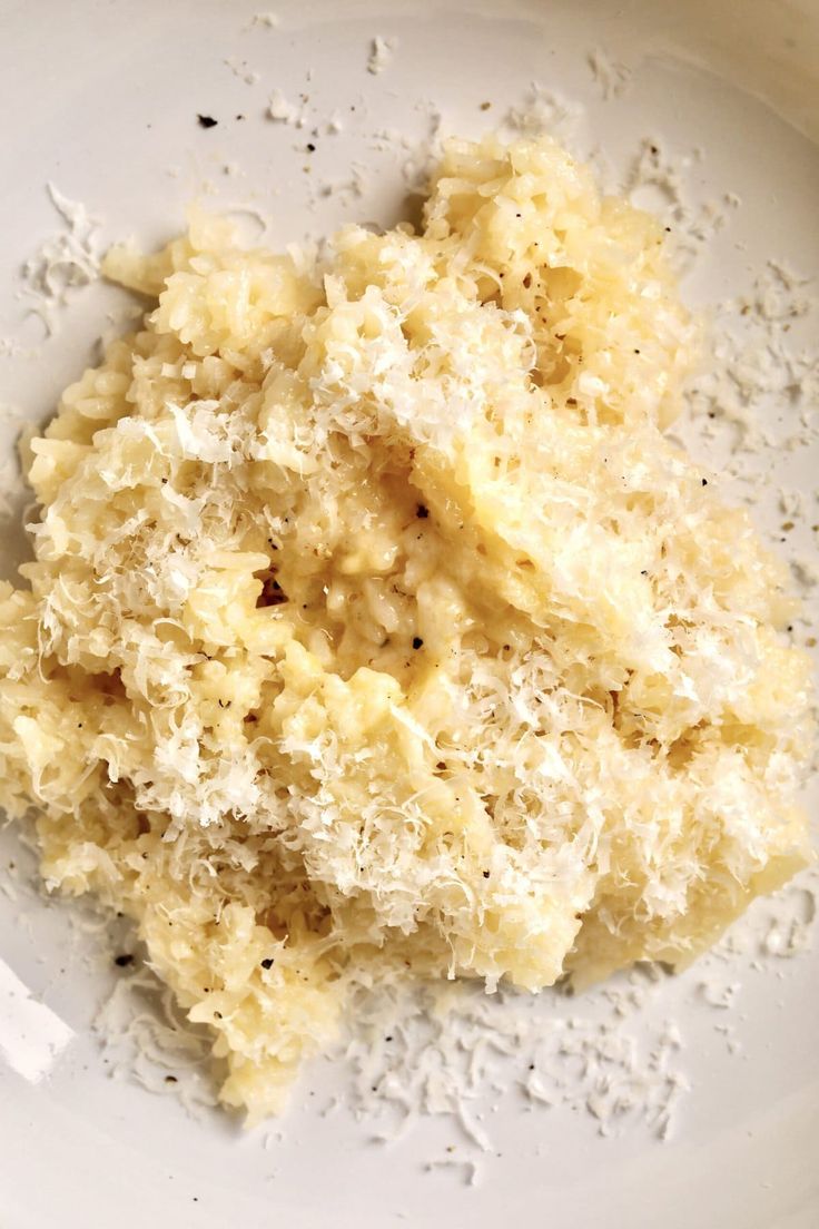 a white plate topped with mashed potatoes and parmesan cheese