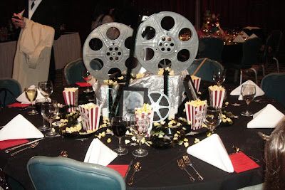 a movie themed table setting with popcorn buckets and film reel on the centerpiece