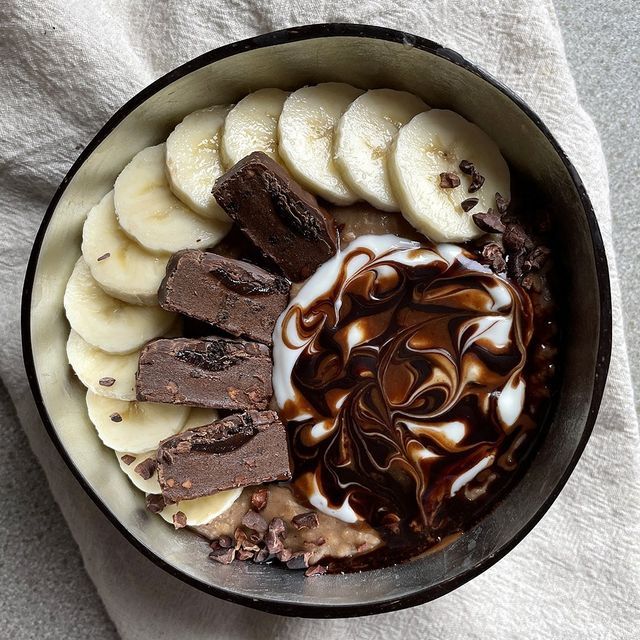 a bowl filled with chocolate and bananas on top of a white cloth next to a spoon