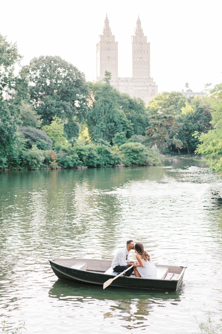 a man and woman are in a boat on the water with trees around them,