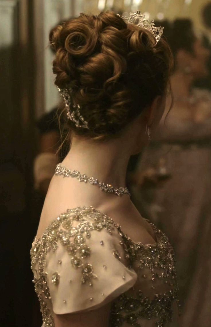 the back of a woman's head wearing a tiara and dress with pearls on it