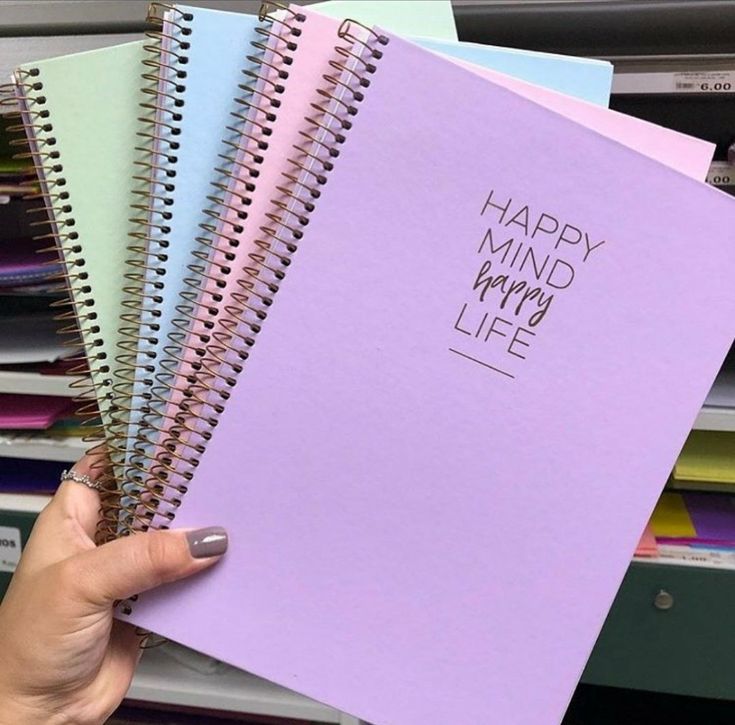 a person holding three spiral notebooks with the words happy mind my life written on them