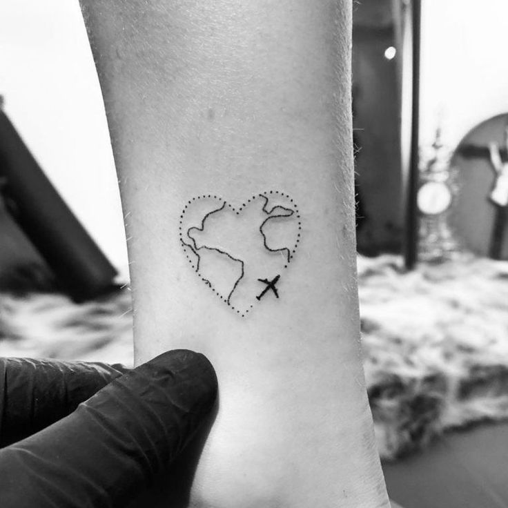 a heart shaped tattoo with an airplane in the middle on someone's left arm