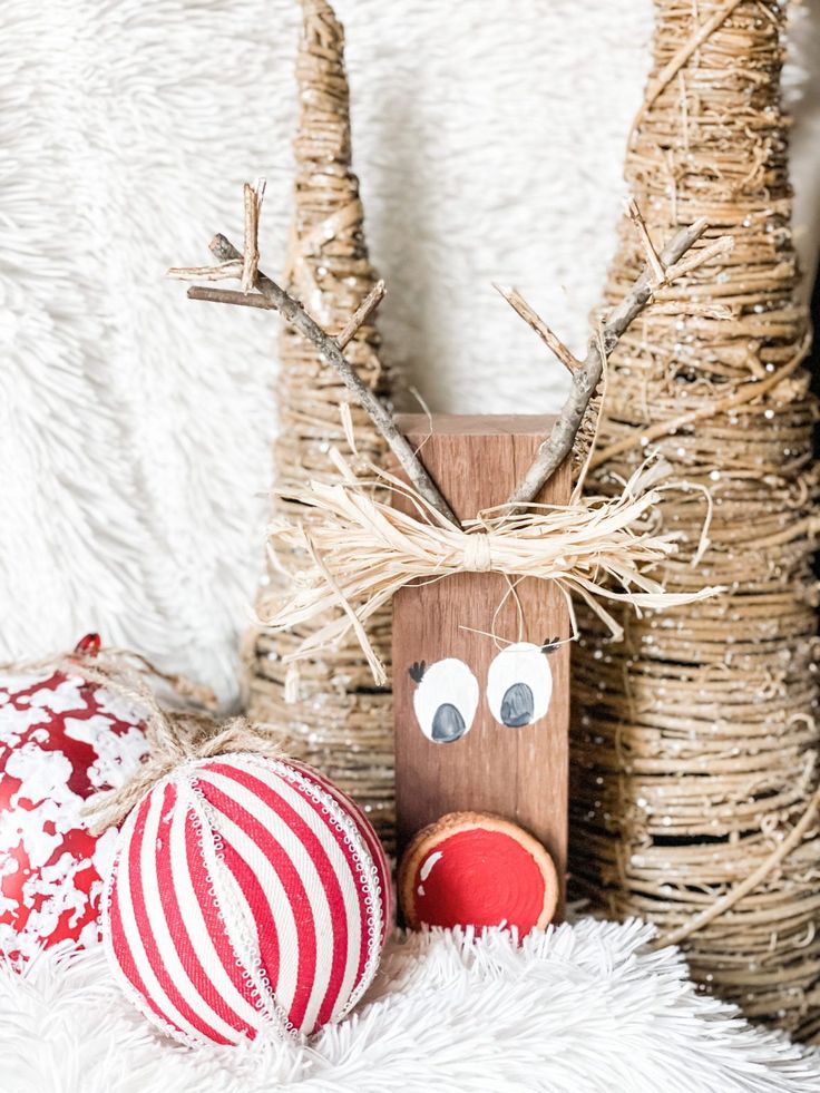 a wooden reindeer head sitting next to two christmas ornaments