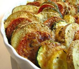 a white dish filled with cooked zucchini and tomatoes