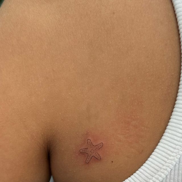 a small tattoo on the back of a woman's left side stomach, with a starfish