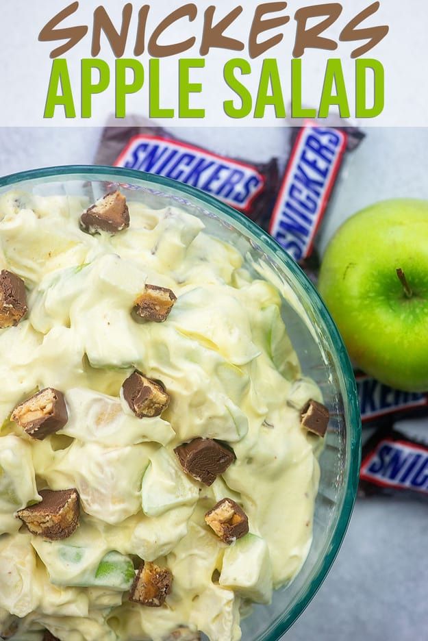 a bowl filled with apple salad next to an apple and two candy bar wrappers