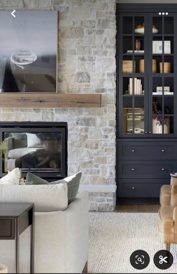 a living room filled with furniture and a fire place in front of a stone wall