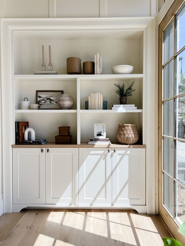 a white bookcase filled with lots of books and vases on top of it