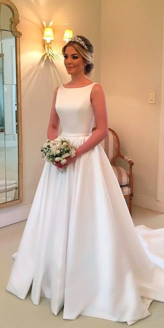 a woman in a white wedding dress standing next to a mirror and holding a bouquet