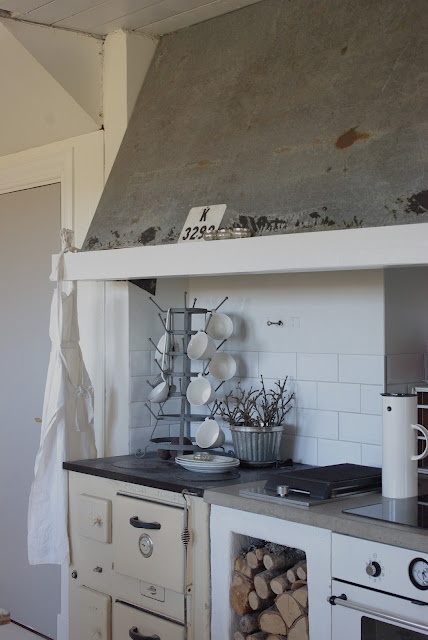 a stove top oven sitting inside of a kitchen next to a wall covered in logs