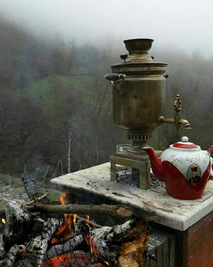 a kettle sitting on top of a stove next to a fire