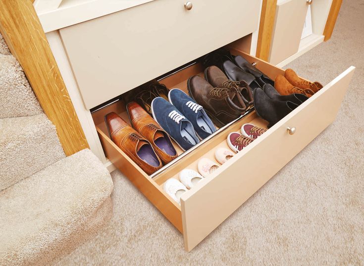 an open drawer with several pairs of shoes in it on the floor next to stairs